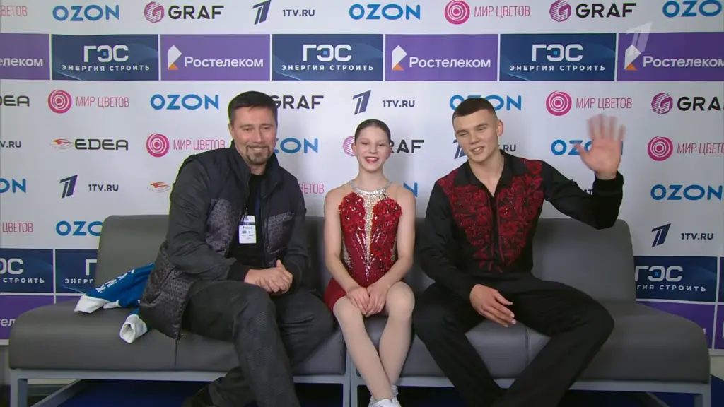 Alexander Samorukov waving beside Darya Tretyakova and their coach