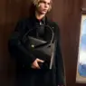 Model Max Stenzel wearing a black Versace ensemble and holding a structured leather handbag inside a luxury train for Versace Holiday 2026