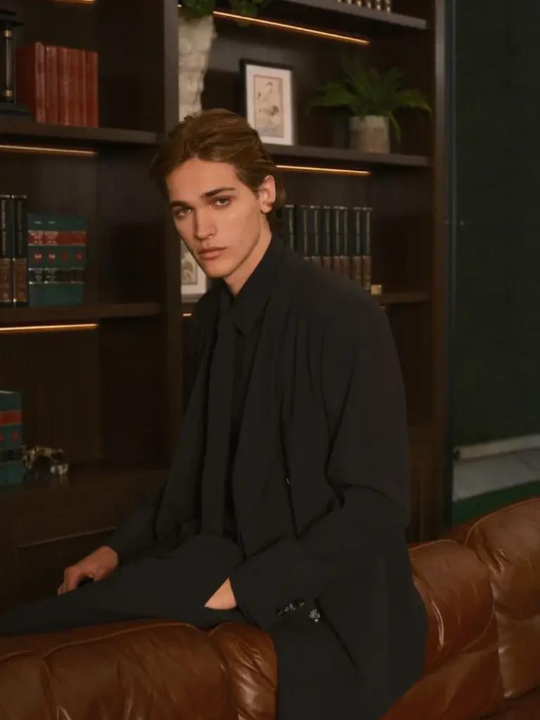 Warren Axelman in a tailored Kith Ivy Fall 2026 look seated on a leather sofa