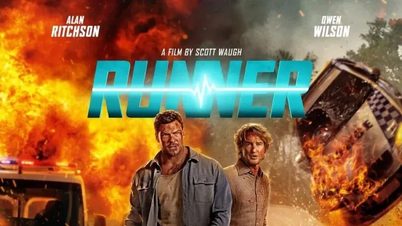 Alan Ritchson and Owen Wilson walk through a fiery scene, with Ritchson holding a handgun and Wilson carrying a medical cooler.