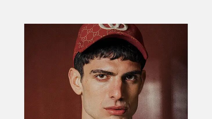 Martin Cols faces the camera in a close portrait wearing a red cap and open white shirt.