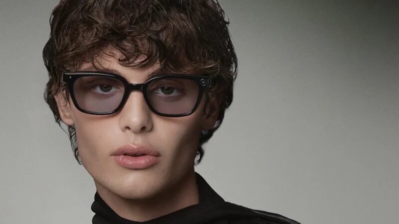 Model wearing black sculptural eyeglasses in a close fashion portrait.