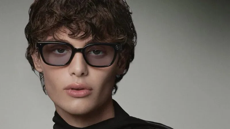 Model wearing black sculptural eyeglasses in a close fashion portrait.