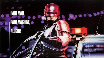 RoboCop stands beside a police car in full armor, holding a firearm, with the slogans “Part man. Part machine. All cop.” and “The future of law enforcement” visible on the original poster.