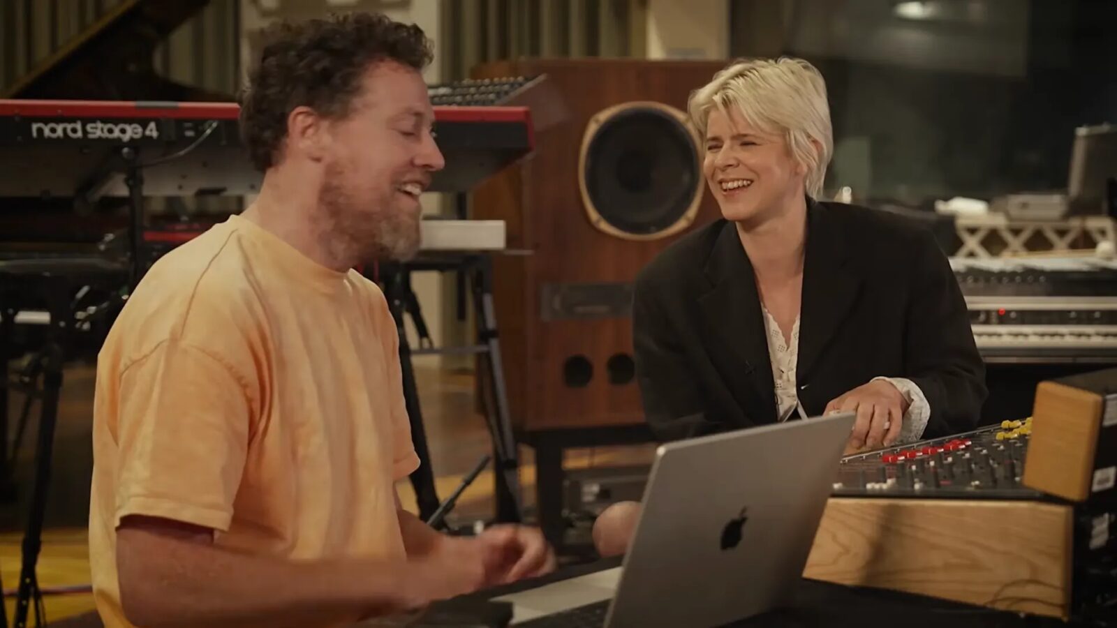 Robyn and Joseph Mount sit together in a recording studio beside a laptop, mixing console and keyboards.