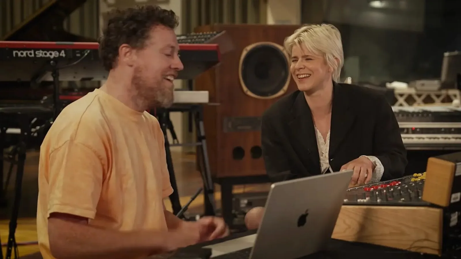 Robyn and Joseph Mount sit together in a recording studio beside a laptop, mixing console and keyboards.