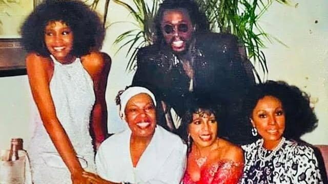 Young Whitney Houston stands beside Roberta Flack, Nickolas Ashford, Valerie Simpson and Diahann Carroll in a posed group portrait.