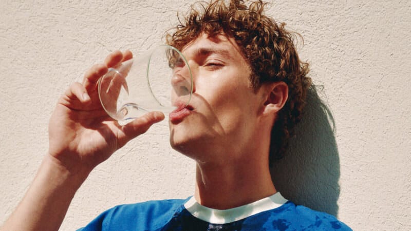 Valentin Humbroich holds a glass near his mouth while wearing a royal-blue T-shirt reading “Thank You For Being A Friend.”