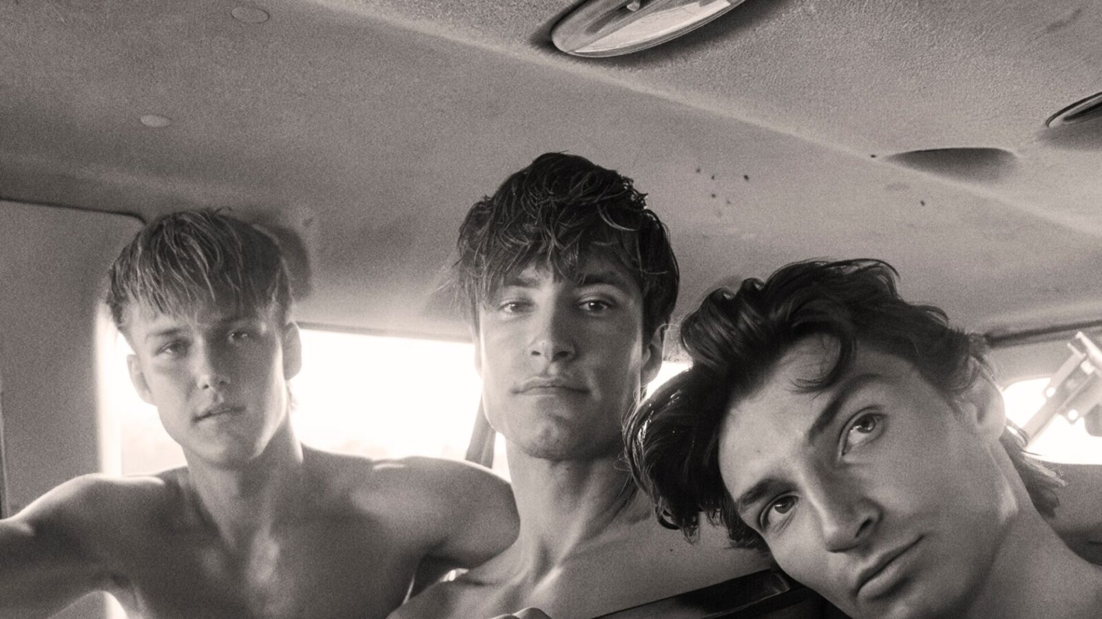 Sean Williams, Danny Andreev and Zachary Borowets pose shirtless together inside a vehicle in a monochrome fashion portrait.